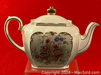 Front view of hexagonal Sadler teapot showing floral basket design on cream porcelain with gold trim