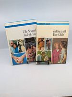 Set of two Woman Alive books from the 1970s, 'The Sexual Side of Love' and 'Talking with Your Child' displayed side by side on stand.
