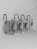 Four identical handcast aluminum clamps aligned side by side showing height, structure, and hook shape.