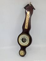 Full view of the antique wooden barometer with three measurement instruments mounted vertically.
