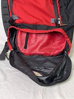 Open front pocket interior of ASOLO backpack showing red lining and zipper detail.
