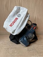 Front view of Bosch electric wood planer with dust bag attached, showing brand name clearly.