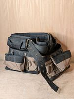 Front view of the Kunys heavy duty builder's tool belt showing multiple beige and black tool pouches and the riveted adjustable strap with buckle.