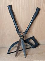 Yardworks clippers showing long metal blades with rust and black handles, positioned open on wooden background.
