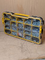Closed view of Dewalt Pro-Organizer with screws visible through transparent lid, showing yellow dividers and black base.