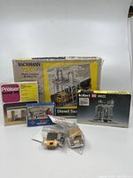 Photo of all six items loosely grouped, showing boxed model kits and two small vehicles sealed in plastic bags.