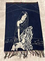 Full view of the indigo batik tapestry showcasing the woman and deer design and colorful fringe at the bottom.