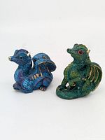 Front and angled side view of blue and green dragon statues showing details and scale.