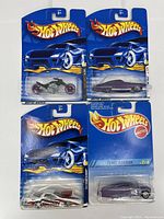 Four sealed Hot Wheels vehicles displayed in original packaging on blue flame-themed backing cards.