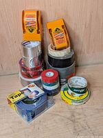 Full lot displaying rolls of tape and Gorilla brand tape applicators on wood surface.
