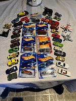 Overall collection of vintage die-cast cars and planes laid out on surface including packaged and loose items