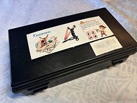 Black plastic case with Kainokai label showing slingshot illustration and warnings.