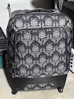 Front view of the large Hays suitcase showing patterned fabric front, hard shell base, and front pocket with emblem.