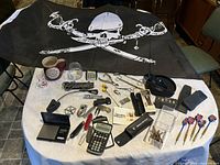 Overall lot arranged on table including pirate flag, mug, darts, scales, and other items