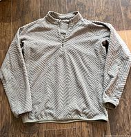 Front view of men's sage green Lululemon textured fleece half-zip sweater laid flat to show overall condition and design.