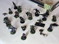 Overview of the full set of approximately 20 Warcraft-themed metal miniature figures displayed on white fabric surface, some showing wear and minor paint chips.