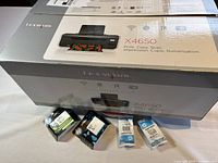 Lexmark X4650 printer box with four ink cartridges placed in front: two black and two color HP cartridges.