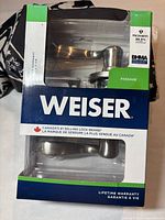 Full view of Weiser door lever set packaging showing two brushed chrome levers and branding details, including lifetime warranty.