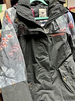 Front view of Roxy ski jacket showing zip front, snap buttons, floral print on sleeves, and chest zipper pocket.