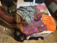 Set of six colorful table runners laid out on a white surface displaying various patterns and colors including stripes, paisley, floral, and silk fabrics.