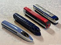 Four model train cars displayed on table, showing varied colors and designs.