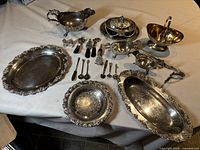 Wide view of entire lot with large tray, covered dish, gravy boats, bowls, spoons, and condiment spreaders arranged on table.