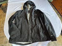 Full view of black L.L. Bean women's Gore-Tex jacket laid flat on a white surface, showing front zipper and hood.