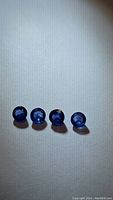 Four round blue sapphires placed in a row on white surface under light showing color and clarity.