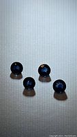 Four round cut blue sapphire gemstones arranged on white surface showing deep blue color and gem facets.