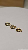 Three pear cut golden citrine gemstones arranged on a white surface, showing transparency and faceted cuts.