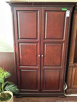 Front view of closed armoire showing paneled doors and metal pulls