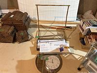 Overview of towel rack, boxed Glacier Bay faucet, boxed expandable drying rack, round wall clock and mirror on floor.