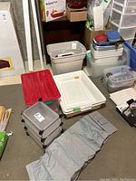 Plastic storage bins of various sizes, clear with red and green lids, cube organizers and food containers.
