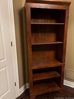 Full view of cherry-finish wooden bookcase showing upper and lower shelving compartments