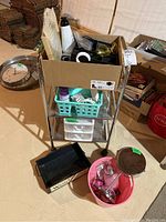 Front angle view of metal mesh storage cart loaded with boxes and various items including sunglasses and accessories on floor