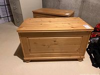 Front view of wood storage chest showing panel design and rounded feet.