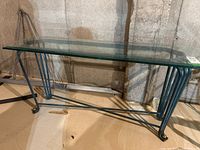Front view of a console table showing metal curved legs and clear glass top.