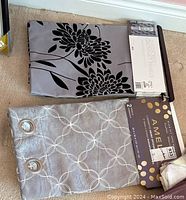 Two new curtain sets displayed, one with gray and black floral patterns and one silver with circular white geometric patterns, showing packaging for identification.