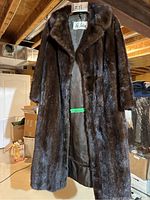 Front view of full-length mink coat on wooden hanger