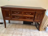 Front view of wood veneer console table showing two middle drawers and two side cabinets with metal pulls, and inset top.