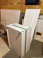 Disassembled white IKEA Malm bed panels stacked vertically with caster wheels on drawers visible.