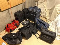 Overall photo showing entire lot: two carry-on suitcases and one large suitcase, plus four duffel bags including one red McDonald's branded bag and multiple black bags of various sizes.