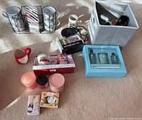 Photo showing multiple items spread on beige carpet including candles, provided mug warmer, fabric storage bin with mugs, and boxed sets of glassware and soap.
