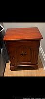Night stand front view showing wood finish and star inlay on the cabinet door.