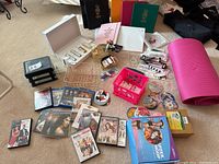 Photo showing binders, DVDs, metal wire baskets, pens, markers, and other small office supplies spread on carpeted floor