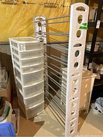 Plastic shoe rack with metal rods and white plastic organizer drawer in basement setting.