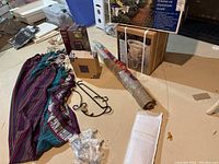 Photo showing colorful striped cotton hammock, rod iron garden hooks, roll of burlap, and LED lantern box alongside solar light box and cabinet pulls.