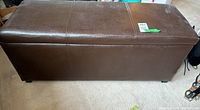 Front view of brown faux leather storage ottoman showing stitching and overall rectangular shape