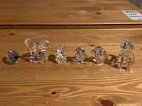 Photo showing all six Swarovski crystal animal figurines in a row on a wooden surface, highlighting size and detail
