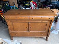 Front view of the vintage oak buffet showing drawers, cabinet doors, wooden knobs, and overall wood grain finish.